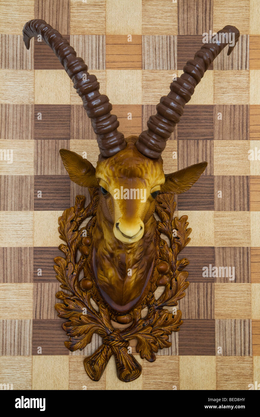 Plastic head of an ibex mounted on imitation wood wallpaper, side view Stock Photo