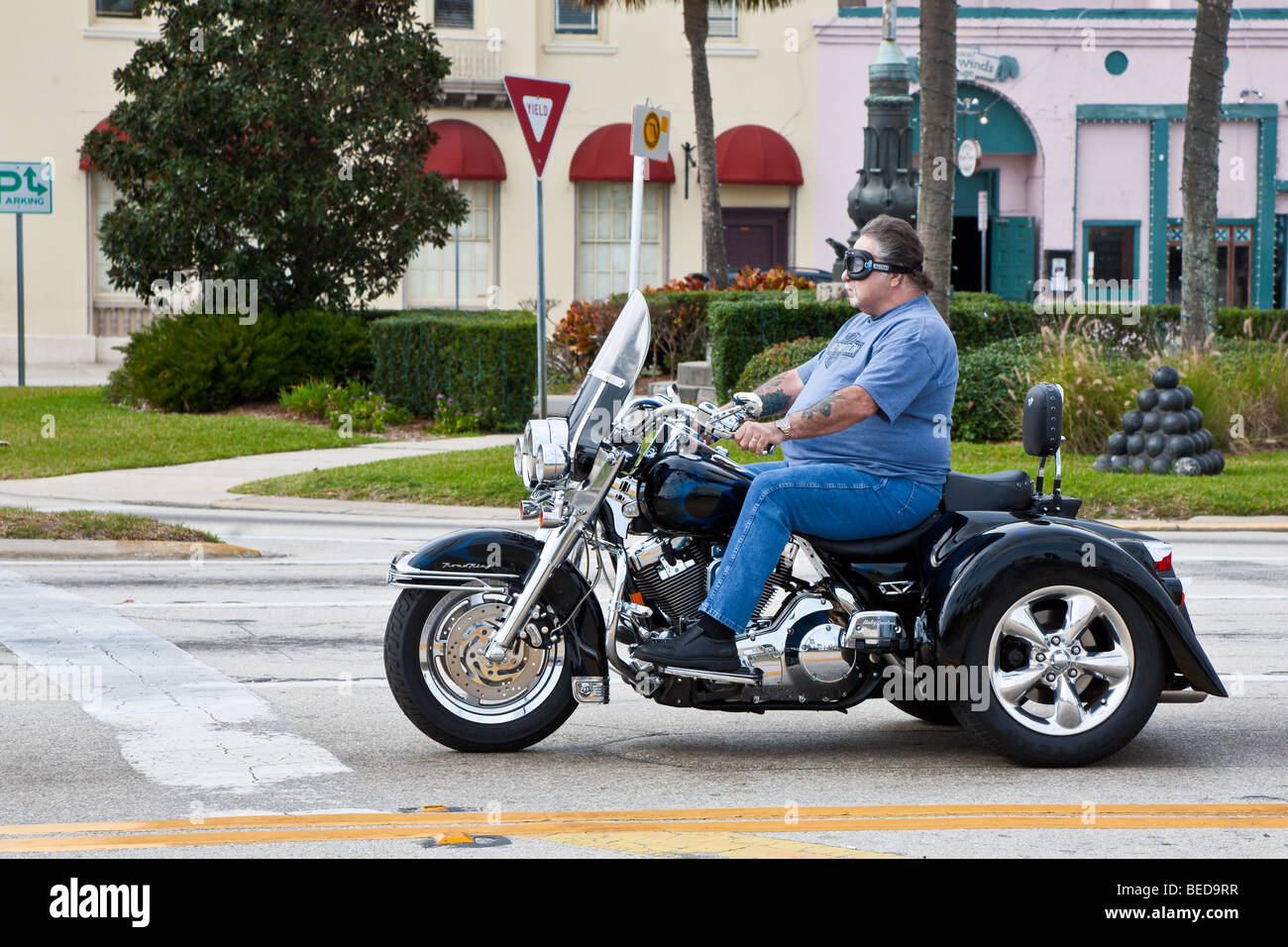 Overweight man riding three wheeled motorcycle through downtown St. Augustine, Florida, USA Stock Photo
