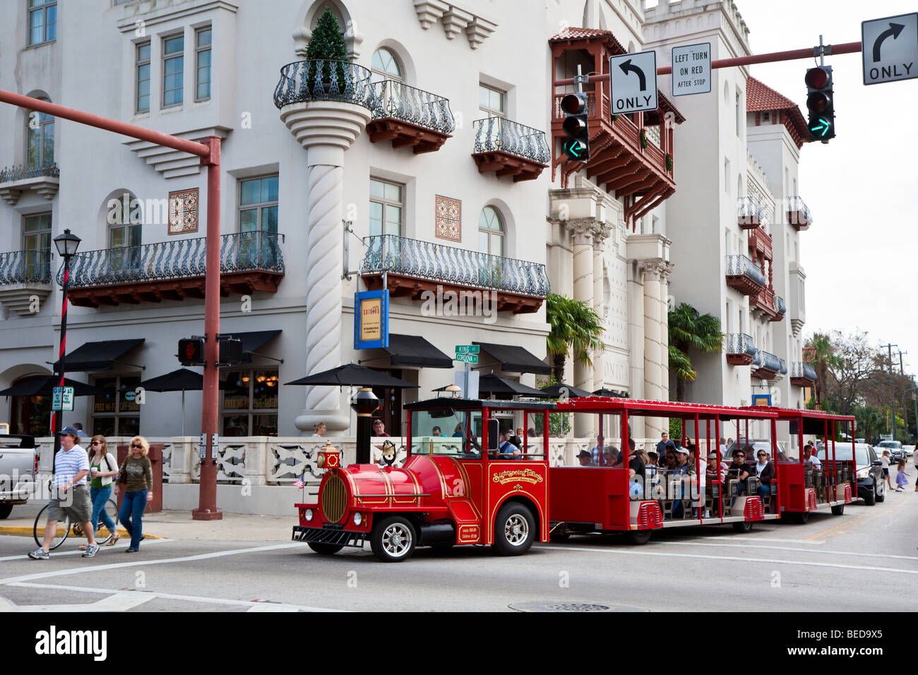 Tourists ride sightseeing train past historic buildings through