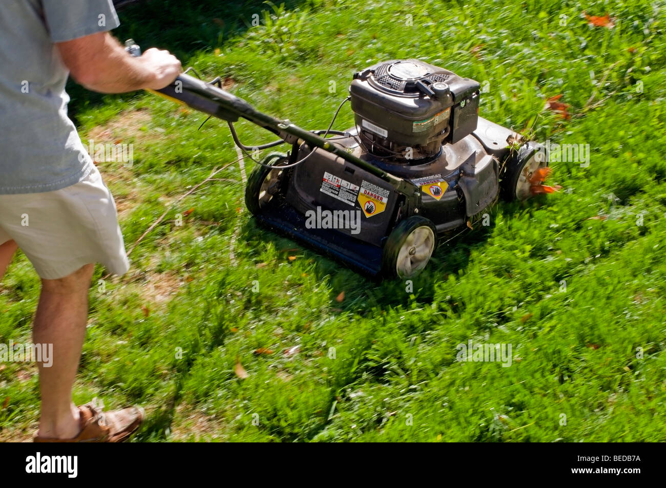 Lawn mower and portion of male shown while actively mowing lawn Stock