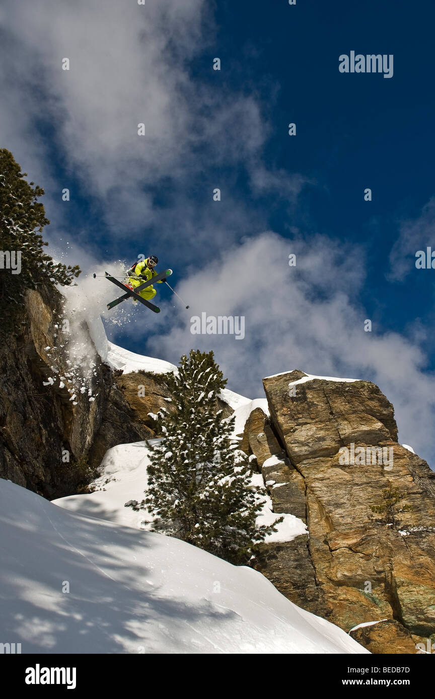 Deep snow skier, freerider, jumping, twist, over a rock wall with ...