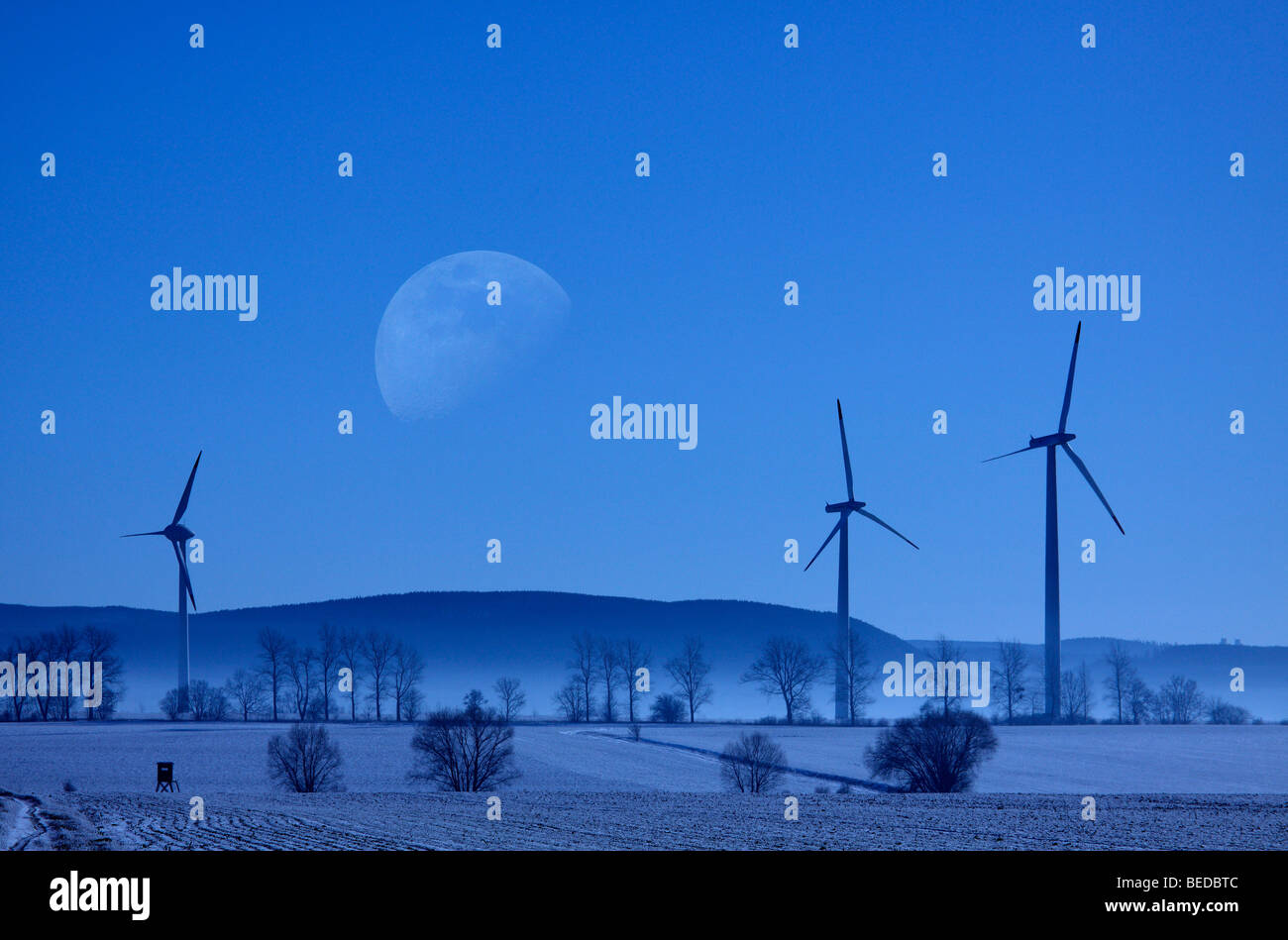 Wintery landscape and wind power plant, big moon, fog Stock Photo