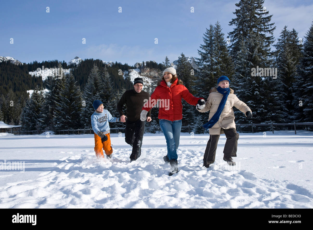 Family running through the snow Stock Photo