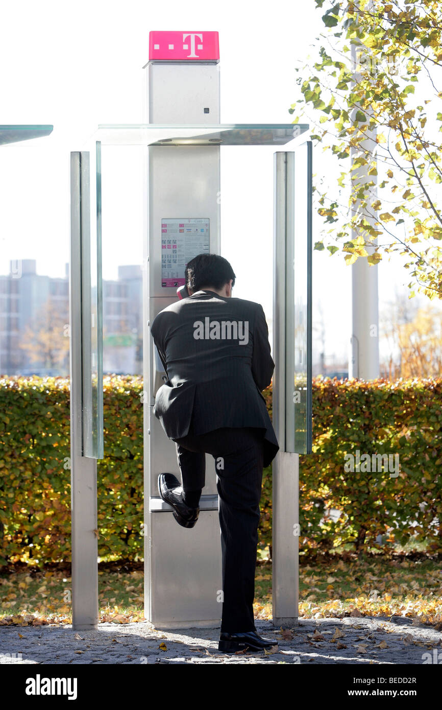 Businessman making a phone call in a public Telekom telephone box, Munich, Bavaria, Germany, Europe Stock Photo