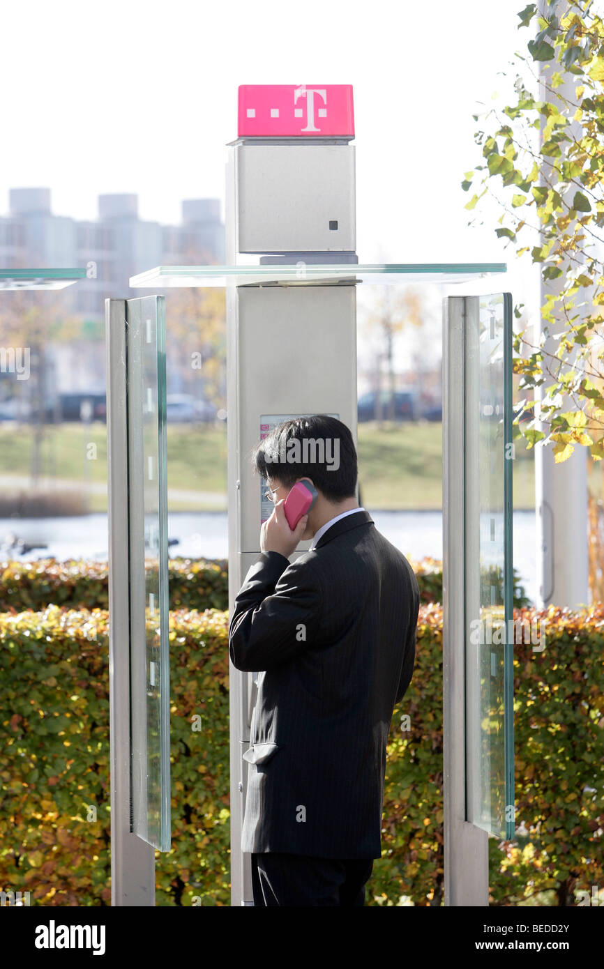 Businessman making a phone call in a public Telekom telephone box, Munich, Bavaria, Germany, Europe Stock Photo