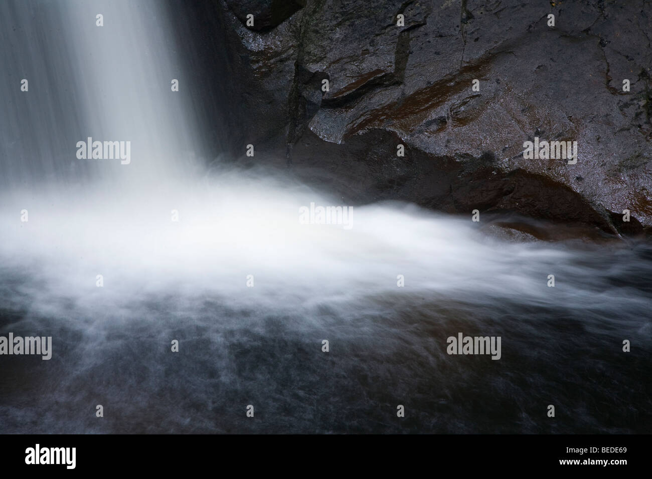 Powerful waterfall crashing down volcanic rock heading for the open sea Stock Photo