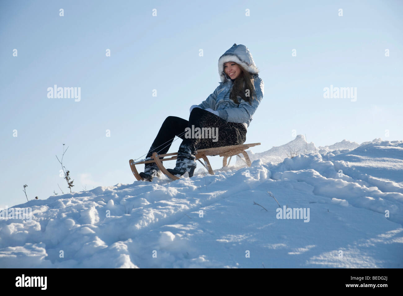 Young woman on a sledge in snow Stock Photo