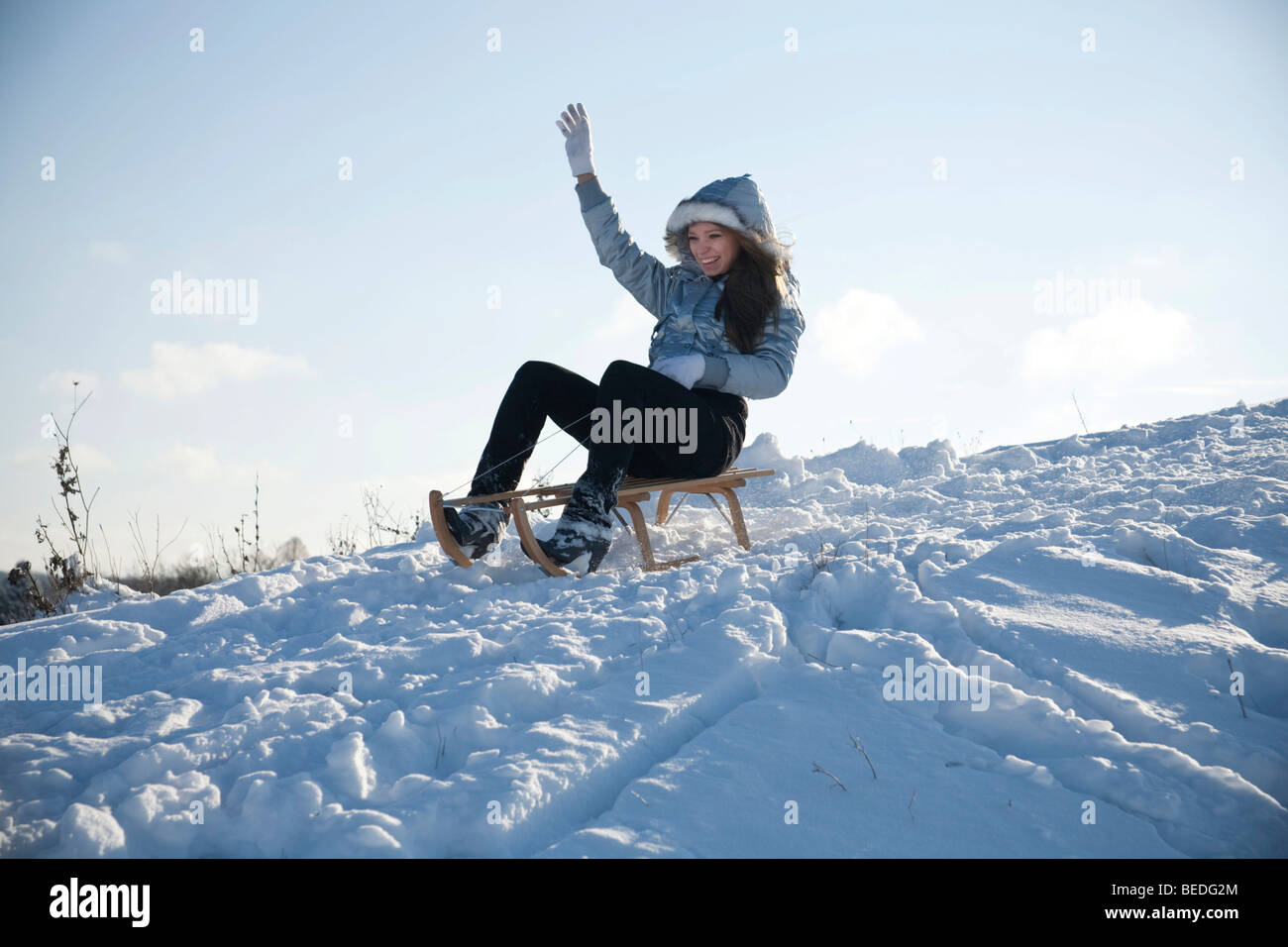 Young woman sledding in snow Stock Photo