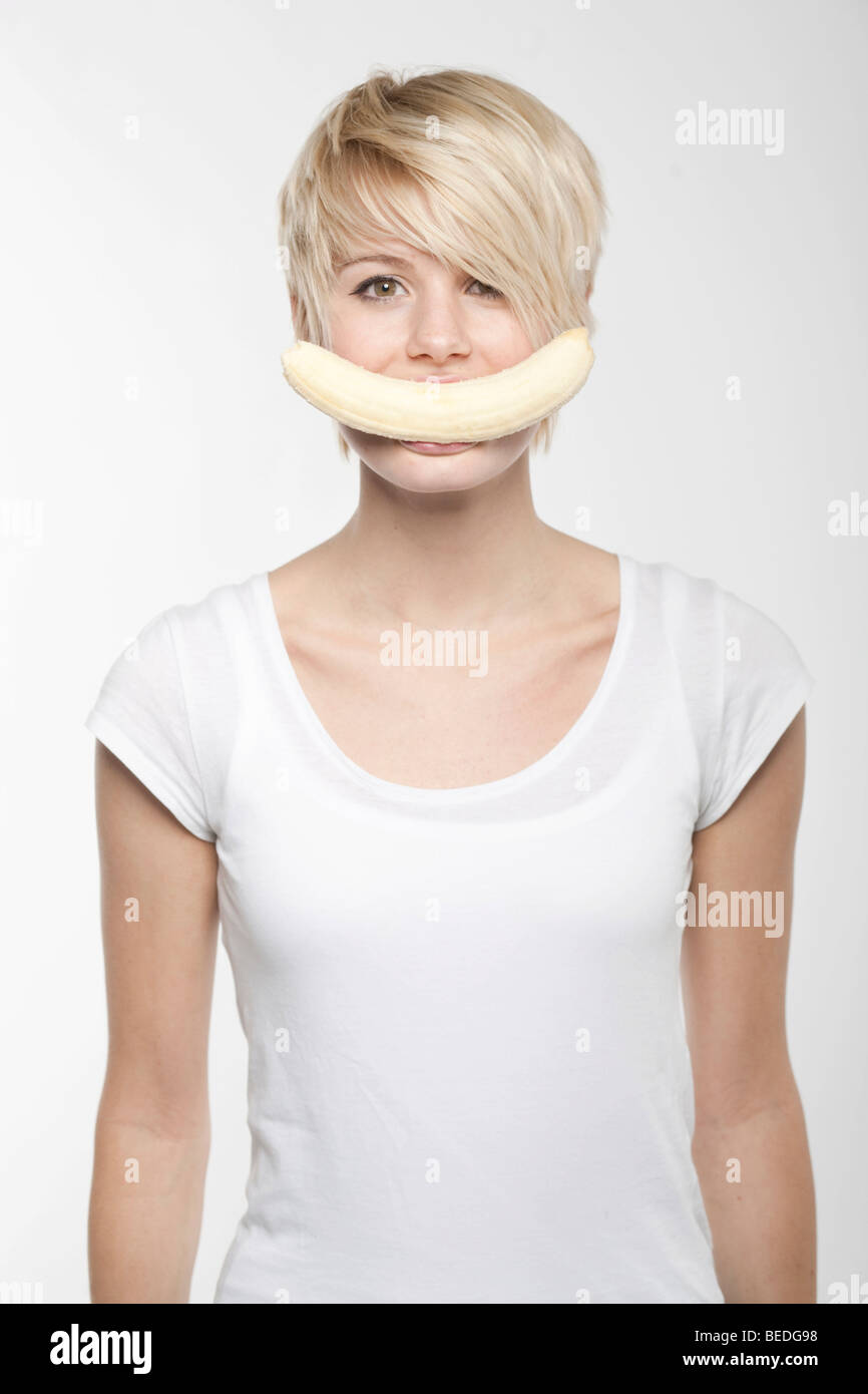 Young woman with short blonde hair, banana in her mouth Stock Photo