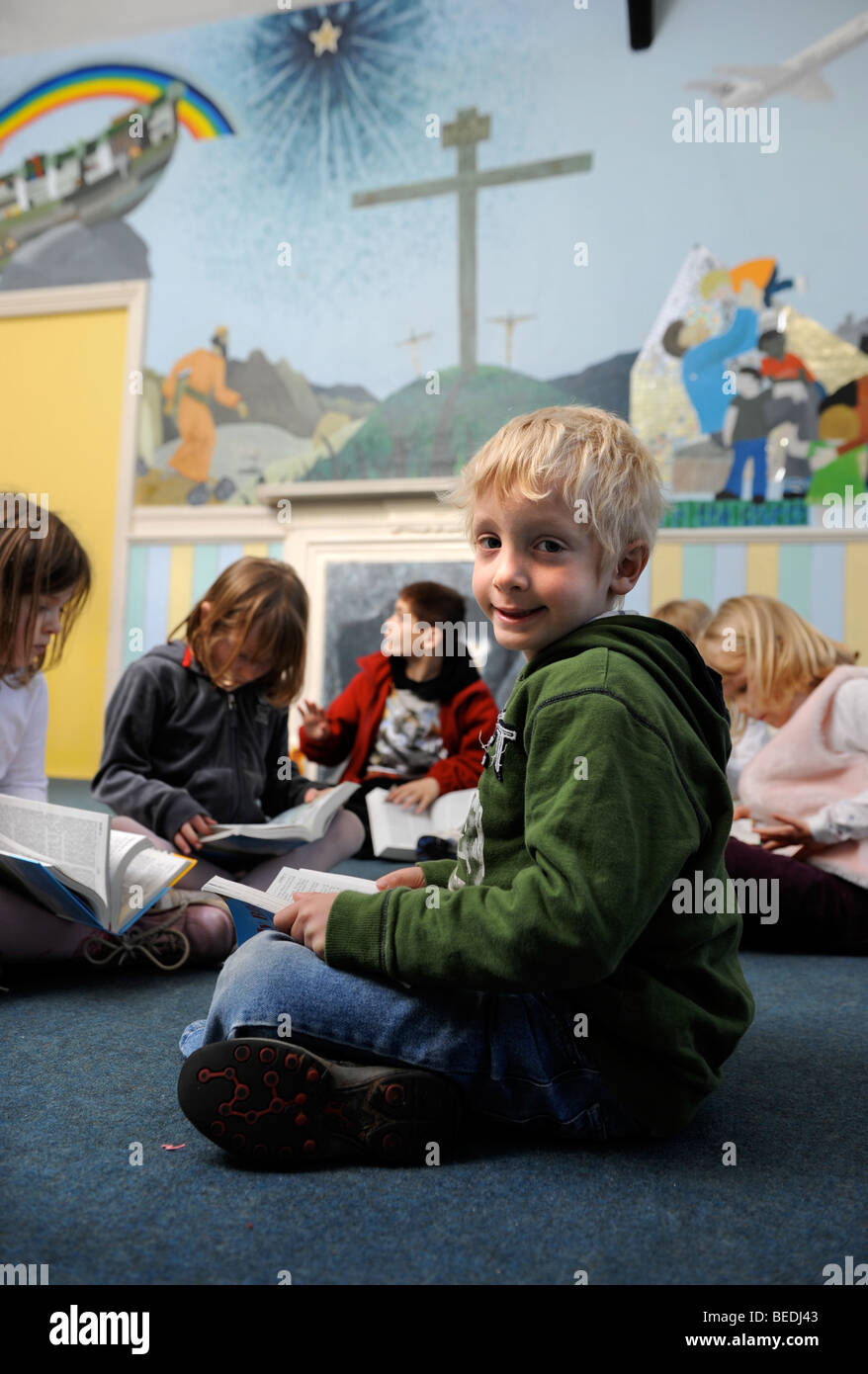 A GROUP OF FOUR GIRLS AND TWO BOYS READING A BIBLE TOGETHER AT A SUNDAY SCHOOL UK Stock Photo