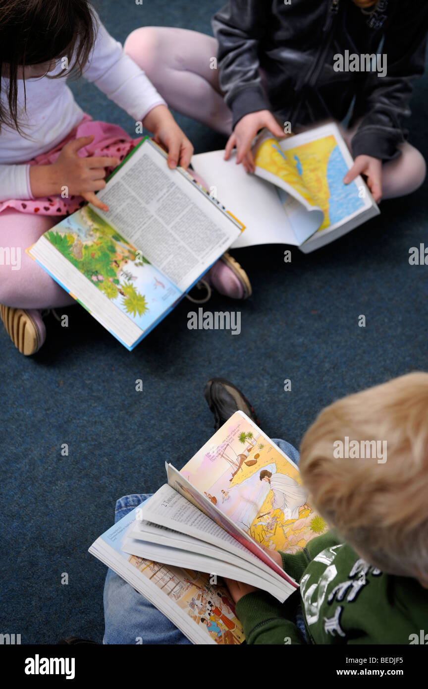 A GROUP OF FOUR GIRLS AND TWO BOYS READING A BIBLE TOGETHER AT A SUNDAY SCHOOL UK Stock Photo