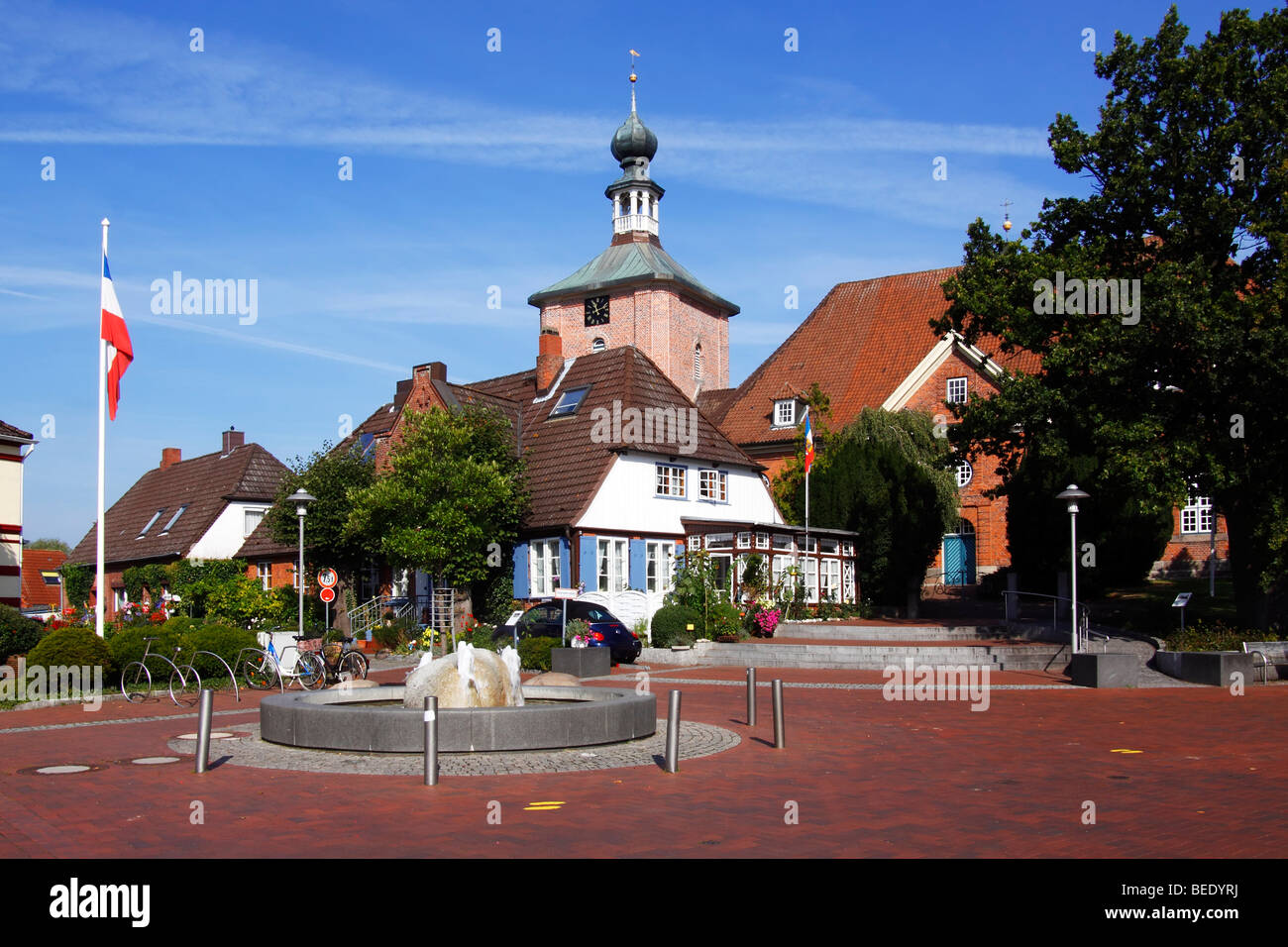 Market place in Schoenberg, fountain, historic houses, protestang church and Schleswig-Holstein flag, Probstei, Ploen district, Stock Photo