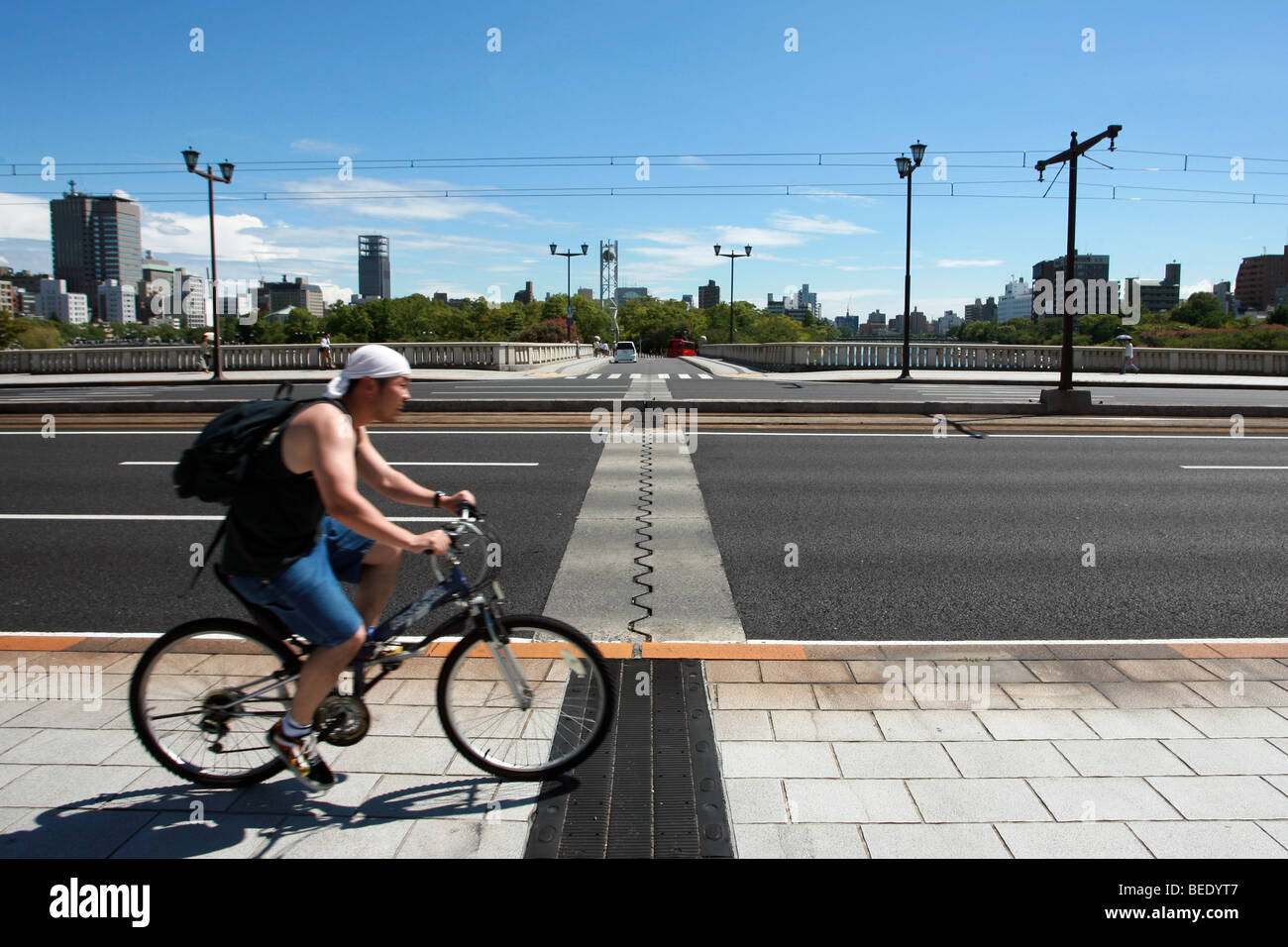 A man cycles over the Aioi bridge in Hiroshima, Japan, which was the target for the first Atomic Bomb 64 years previously. Stock Photo