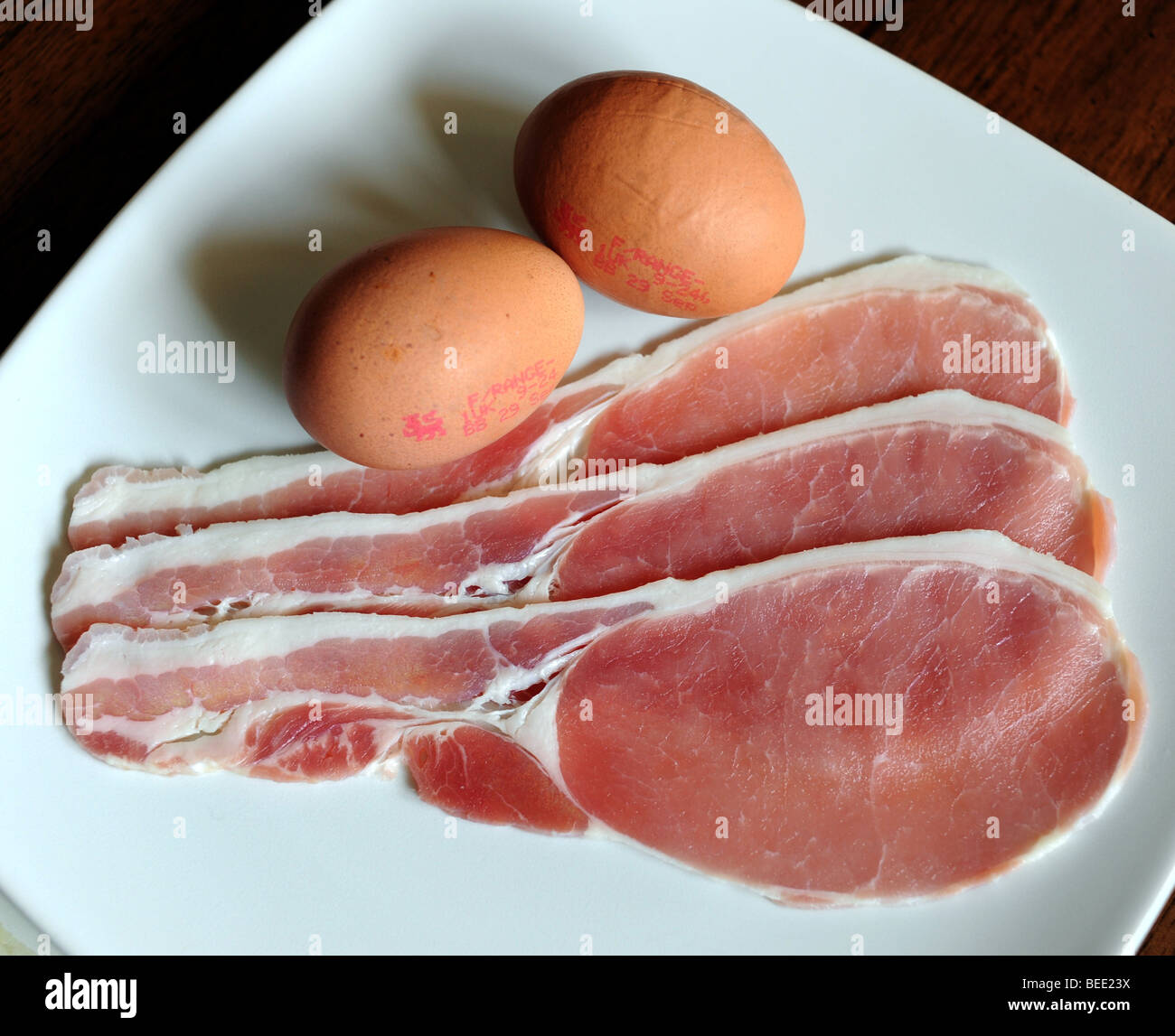 Uncooked plate of bacon and eggs raw food protein Stock Photo Alamy