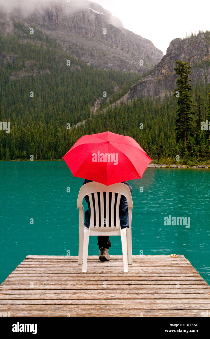 red umbrella with emerald lake water and dock Stock Photo