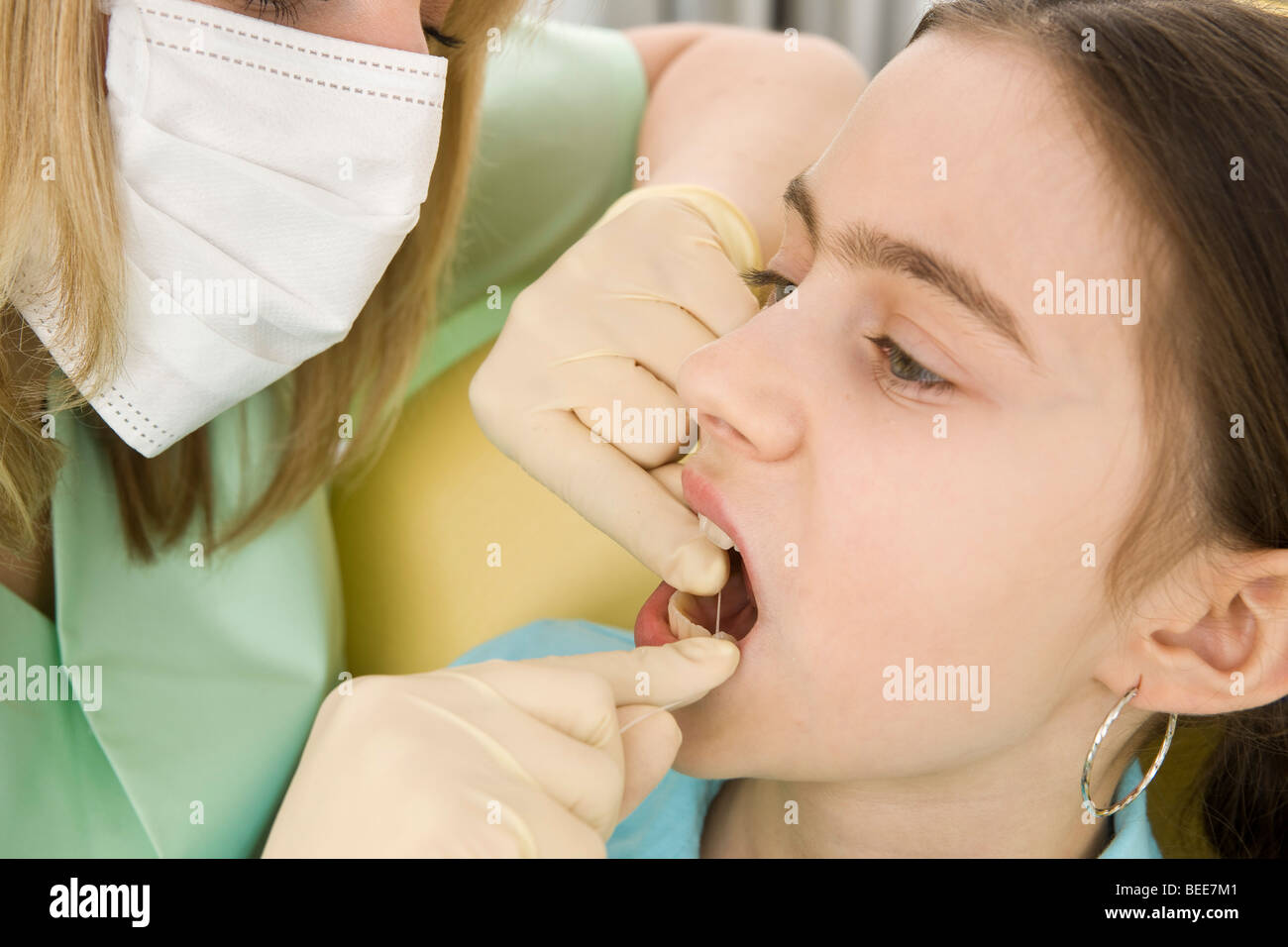 Dental nurse cleaning a girl's teeth with dental floss Stock Photo