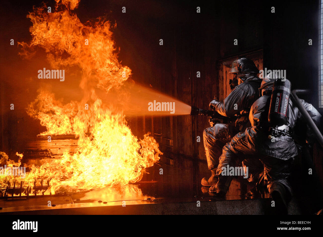 Firefighters  extinguish a simulated battery fire inside an aircraft fire trainer at Royal Air Force Mildenhall, England. Stock Photo