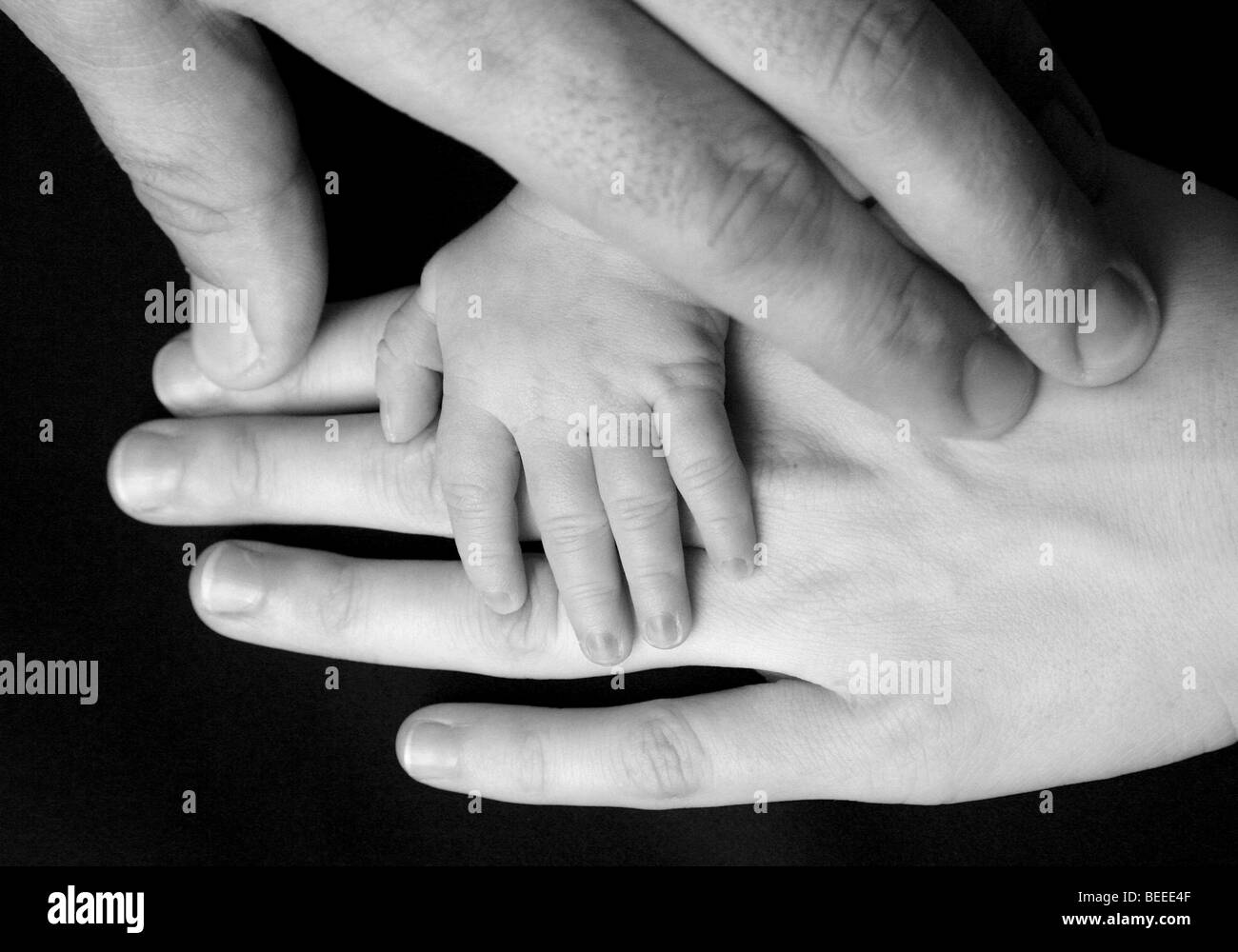 Hands of a family, father, mother and three-week-old baby Stock Photo