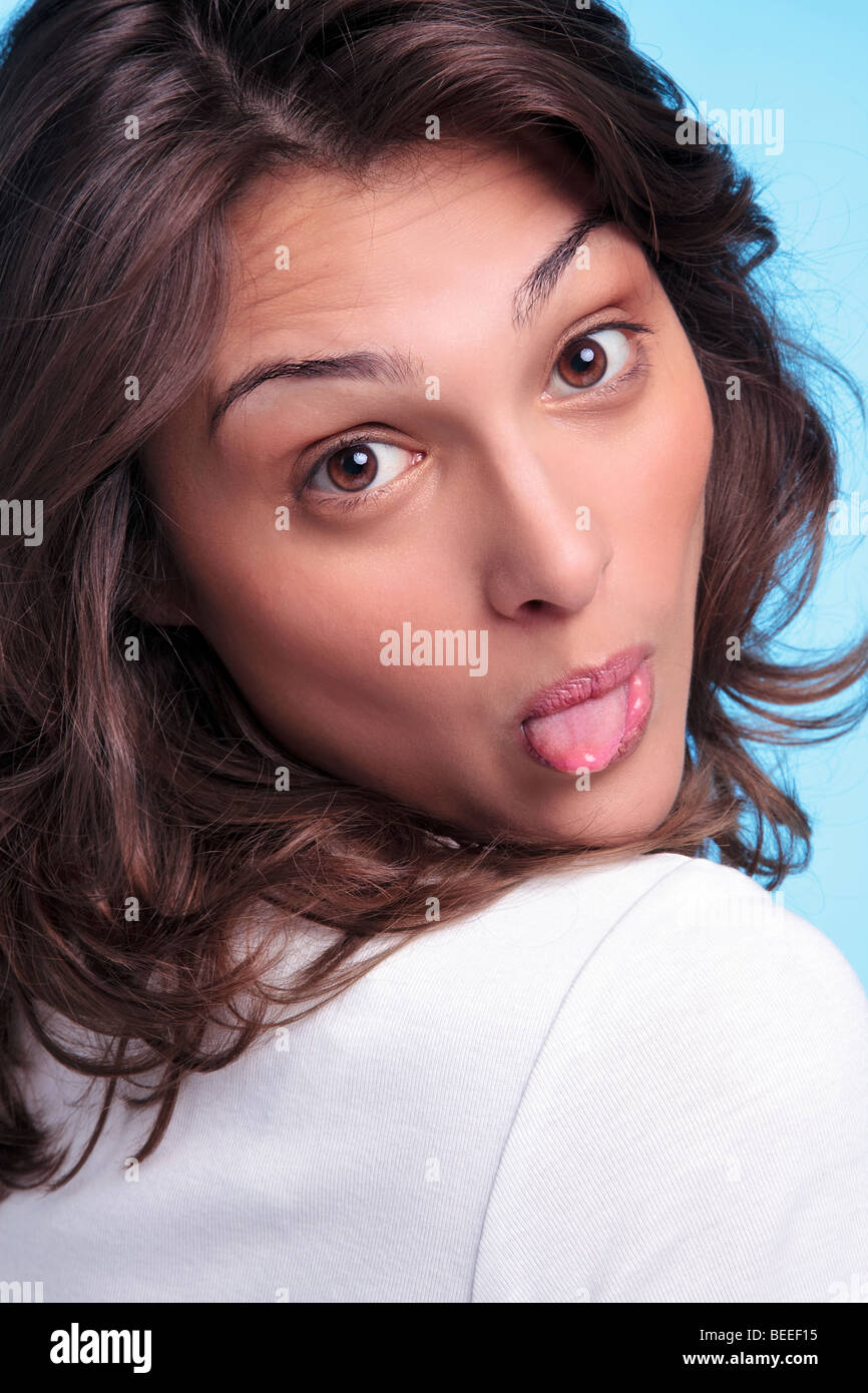 Cheeky brunette woman sticking her tongue out Stock Photo