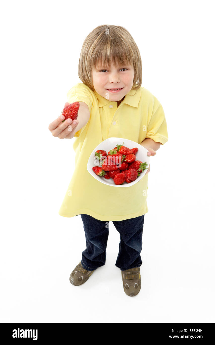 Studio Portrait of Smiling Boy Holding Bowl of Strawberries Stock Photo