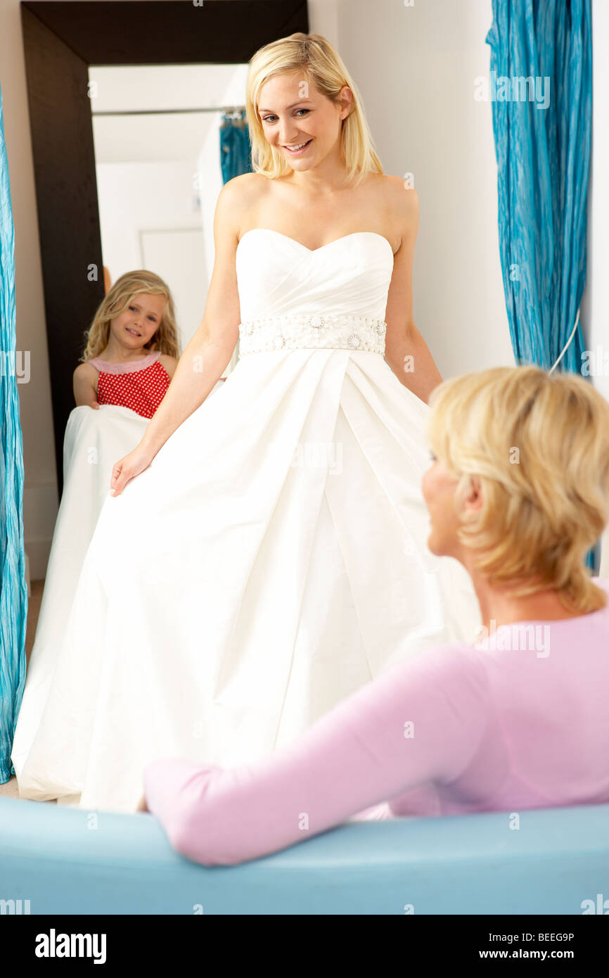 Bride trying on wedding dress with sales assistant Stock Photo Alamy