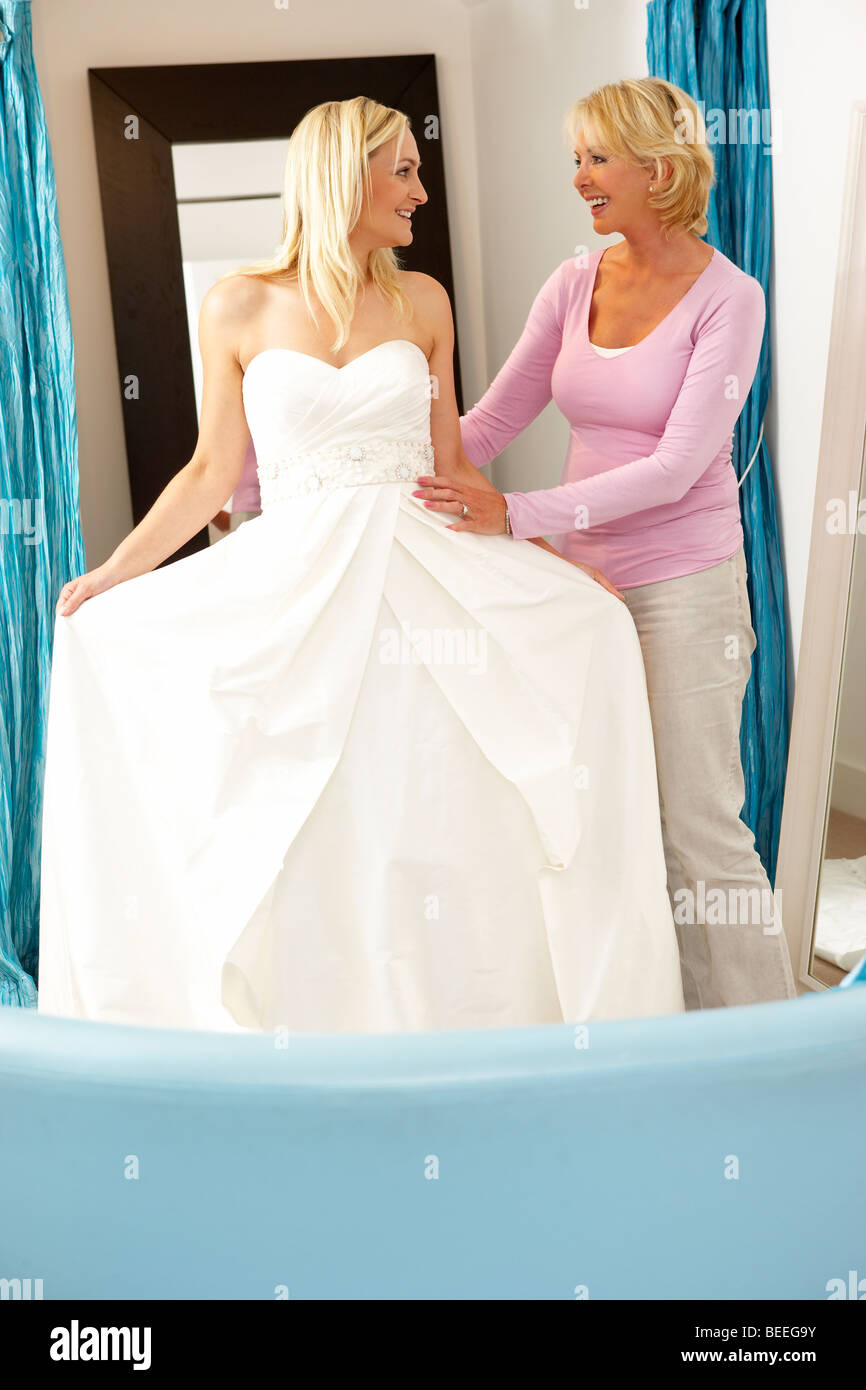 Bride trying on wedding dress with sales assistant Stock Photo Alamy