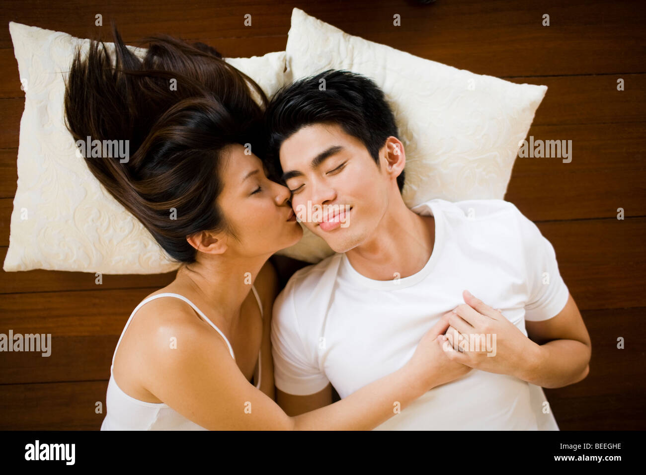 Asian Young couple lying on floor kissing Stock Photo