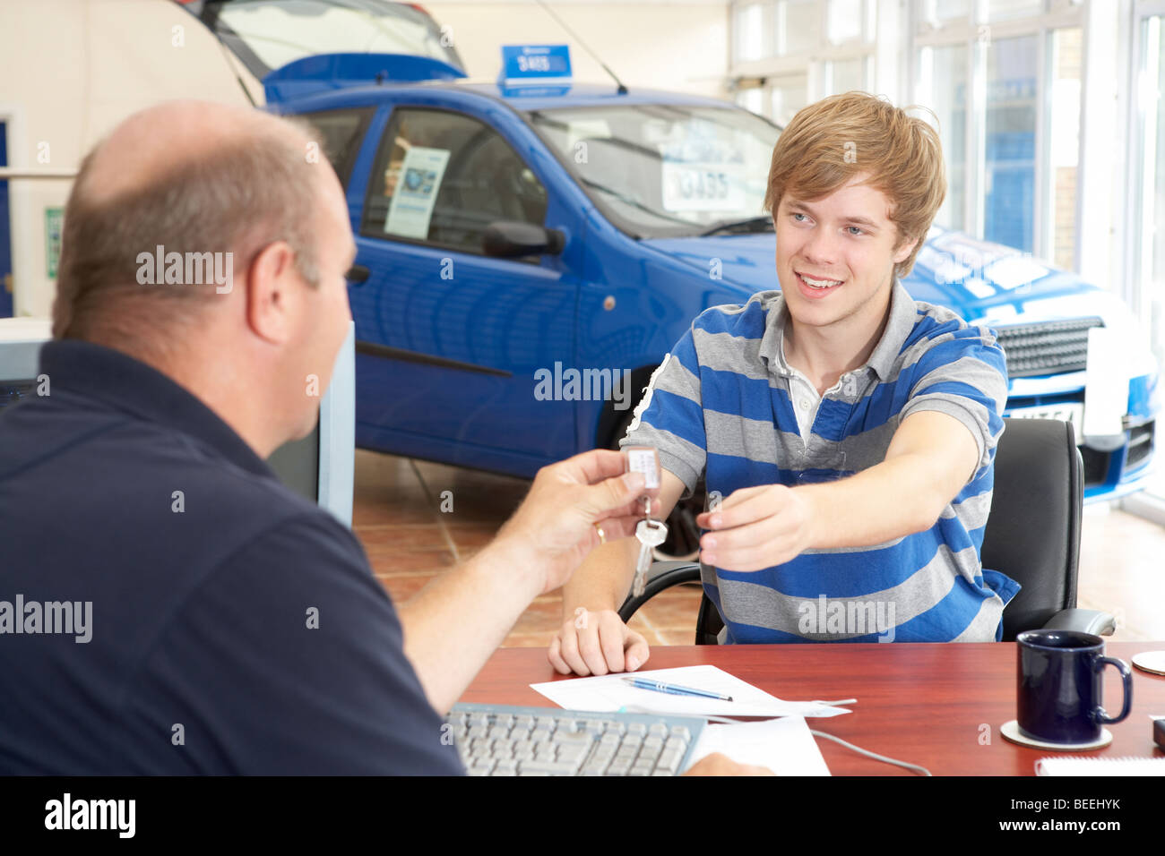 Young man filling in paperwork in car showroom Stock Photo