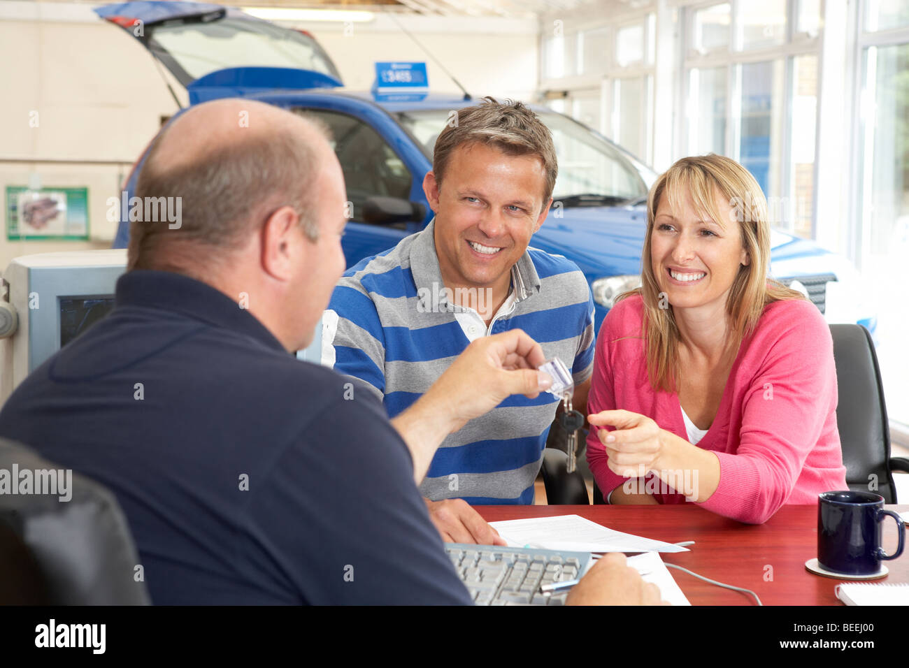 Couple filling in paperwork in car showroom Stock Photo