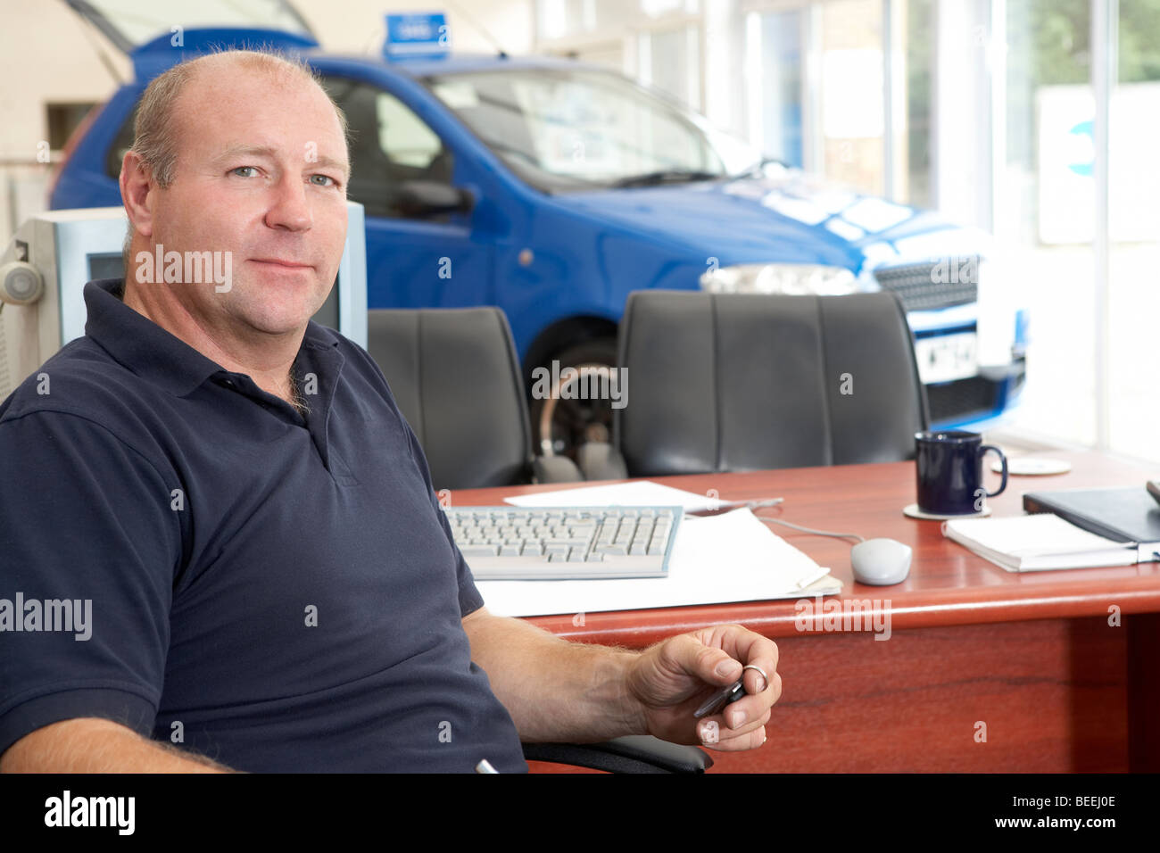 Car salesman sitting in showroom Stock Photo