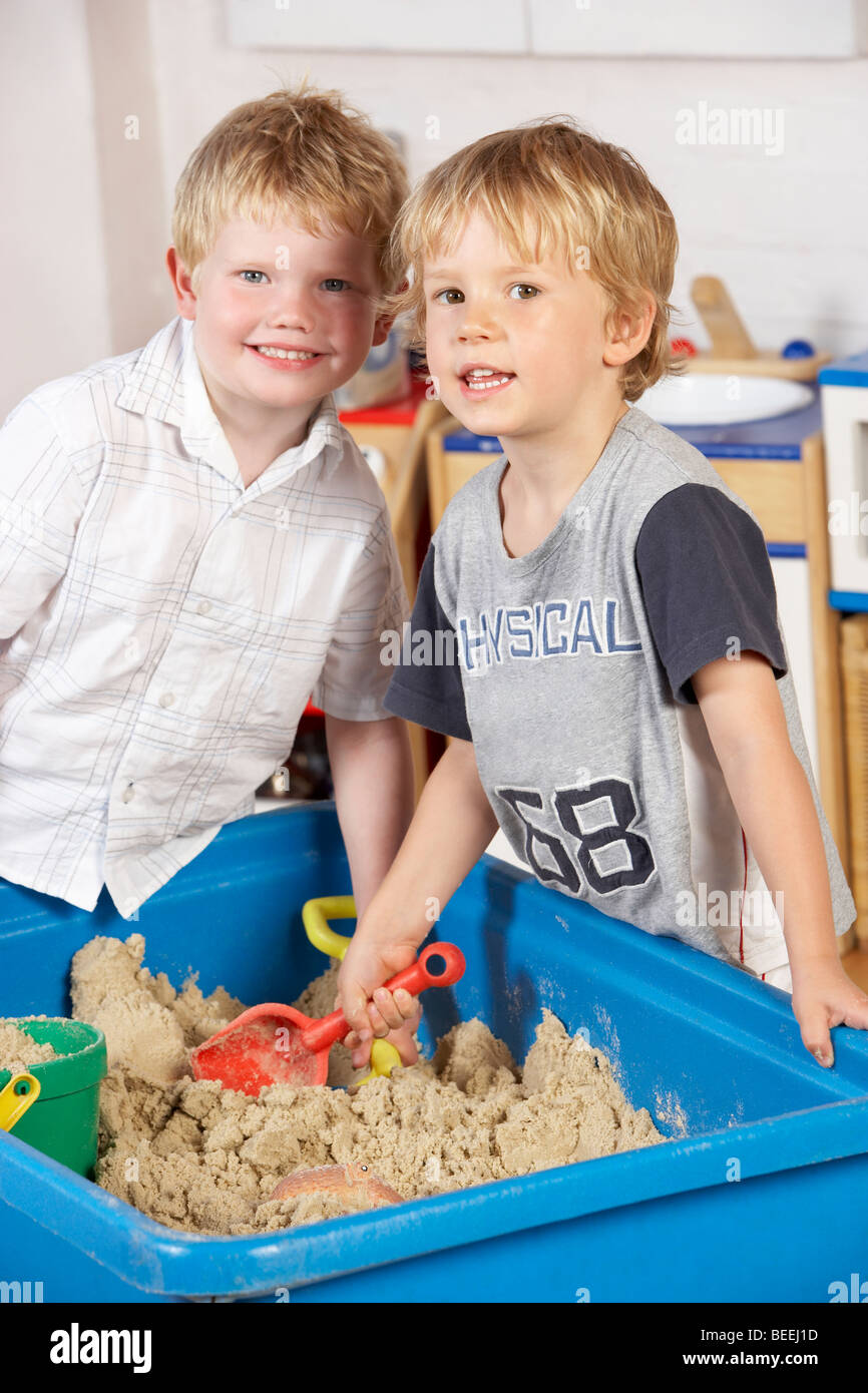 Two Young Boys Playing Together in Sandpit Stock Photo