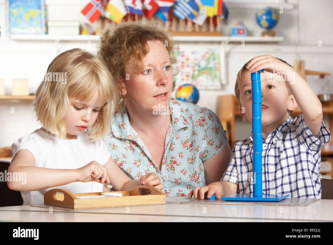 Adult Helping Two Young Children at Montessori/Pre-School Stock Photo