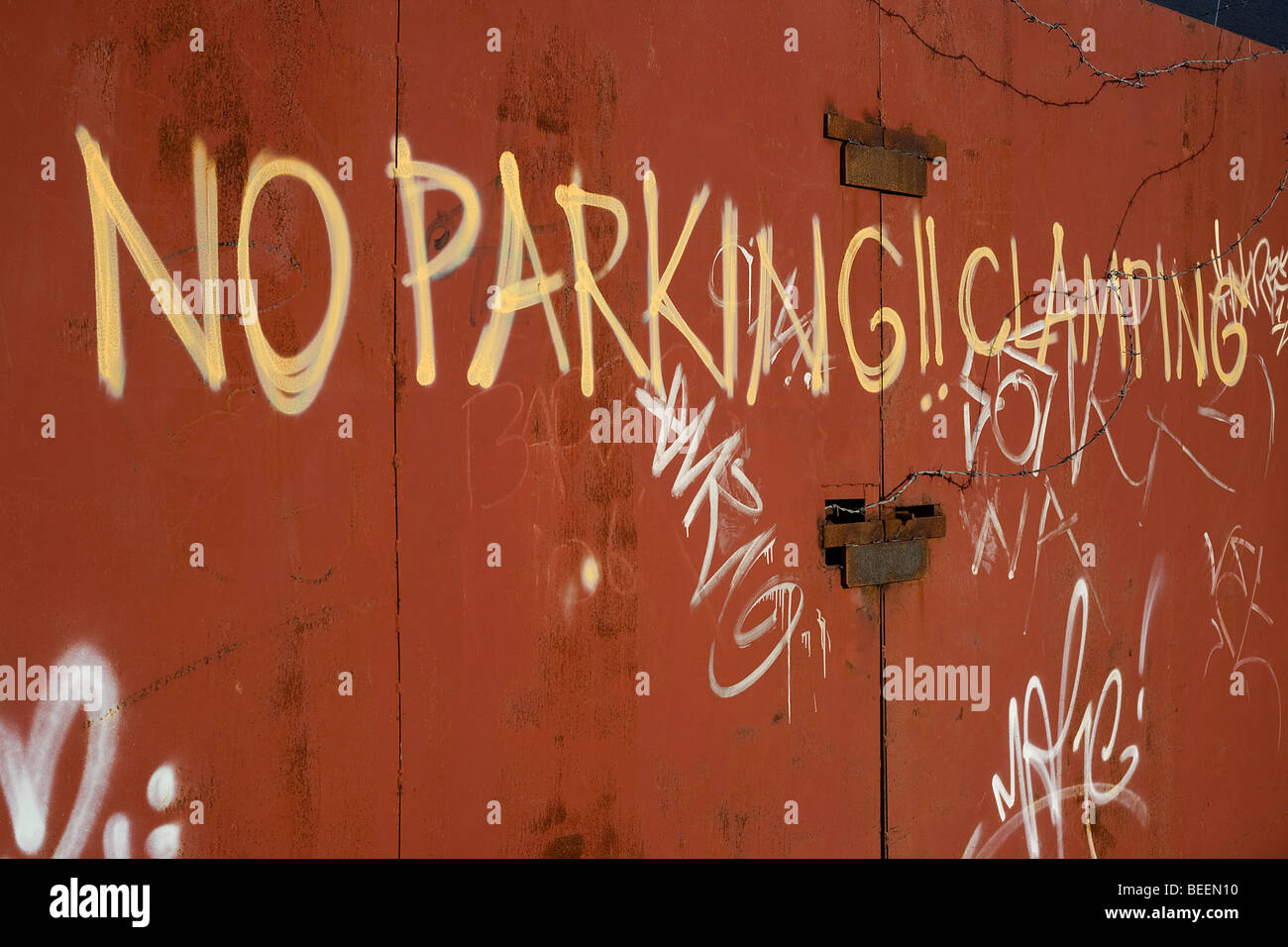 A notice not to park in front of a scrap metal yard, with a threat of clamping, on to gates in an industrial wasteland. Stock Photo