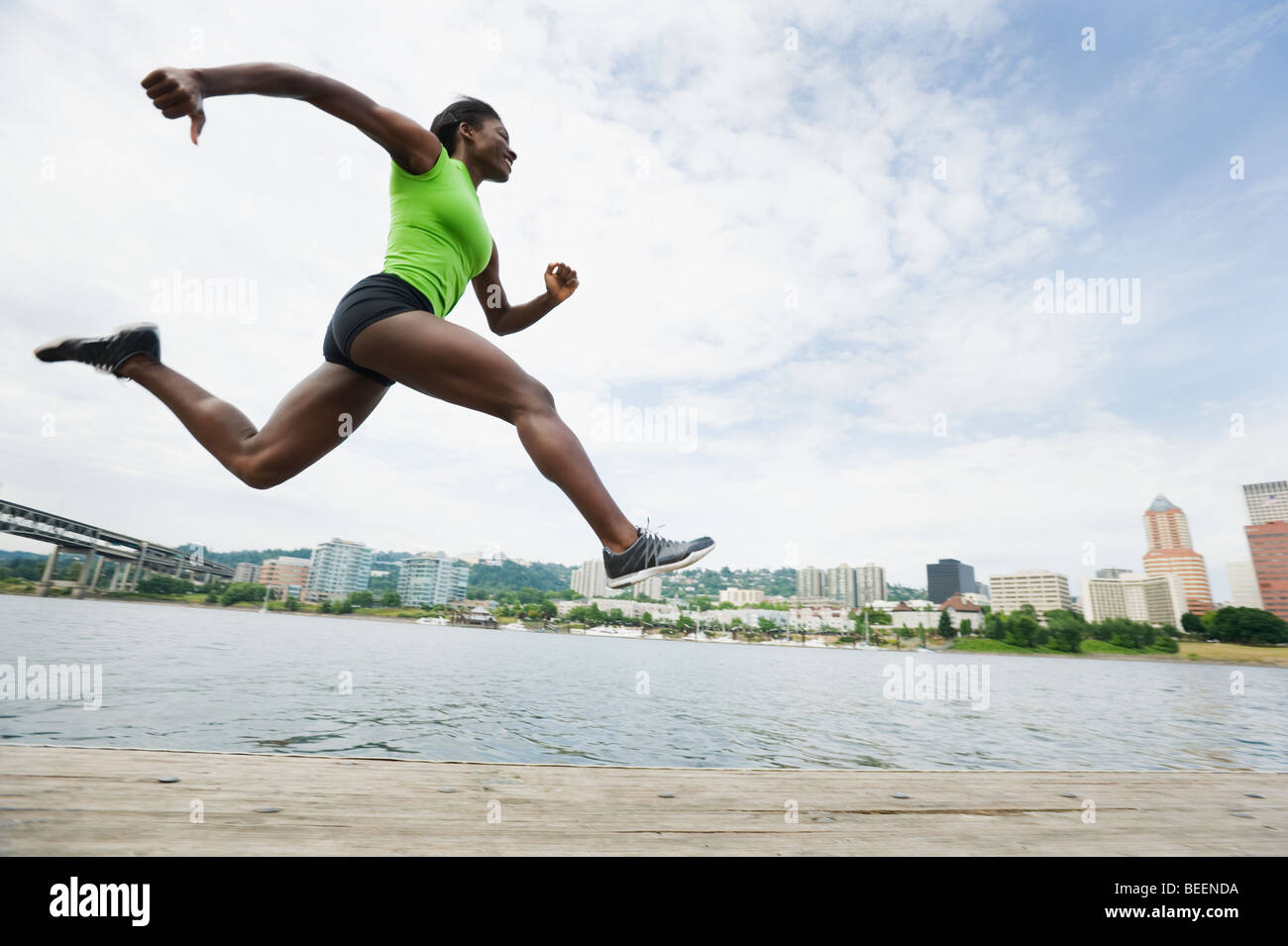 African woman leaping next to river Stock Photo