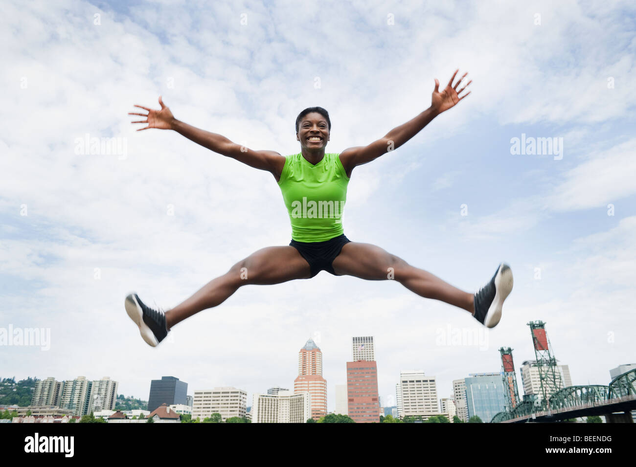 African woman jumping with city in background Stock Photo