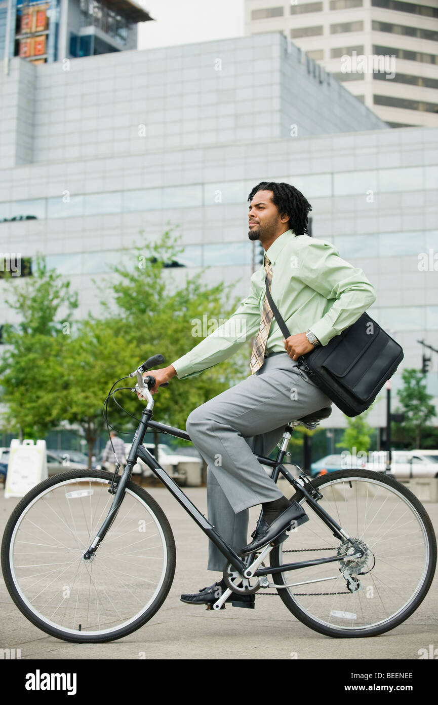 Mixed race businessman riding bicycle in city Stock Photo