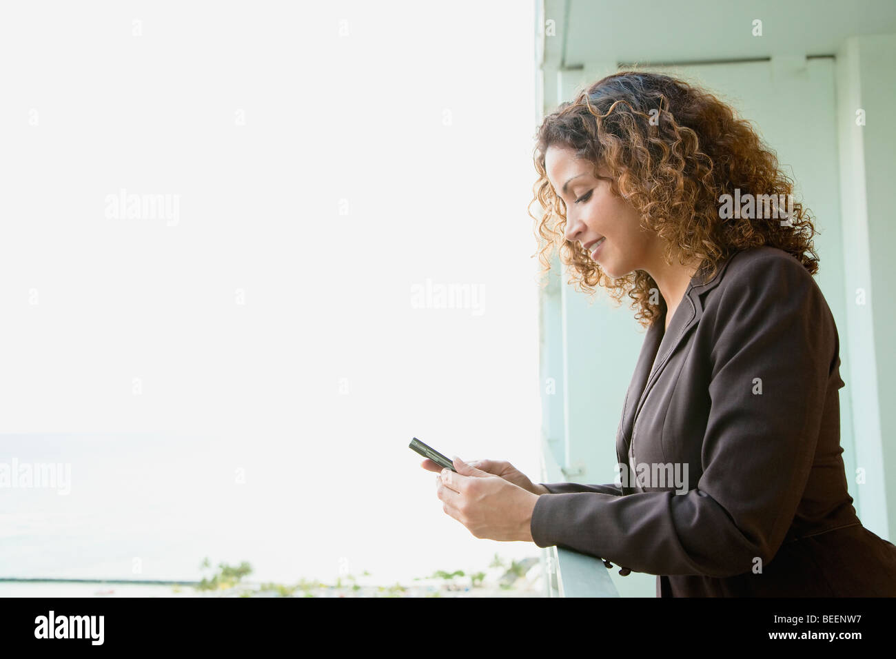 Hispanic woman text messaging on balcony Stock Photo - Alamy