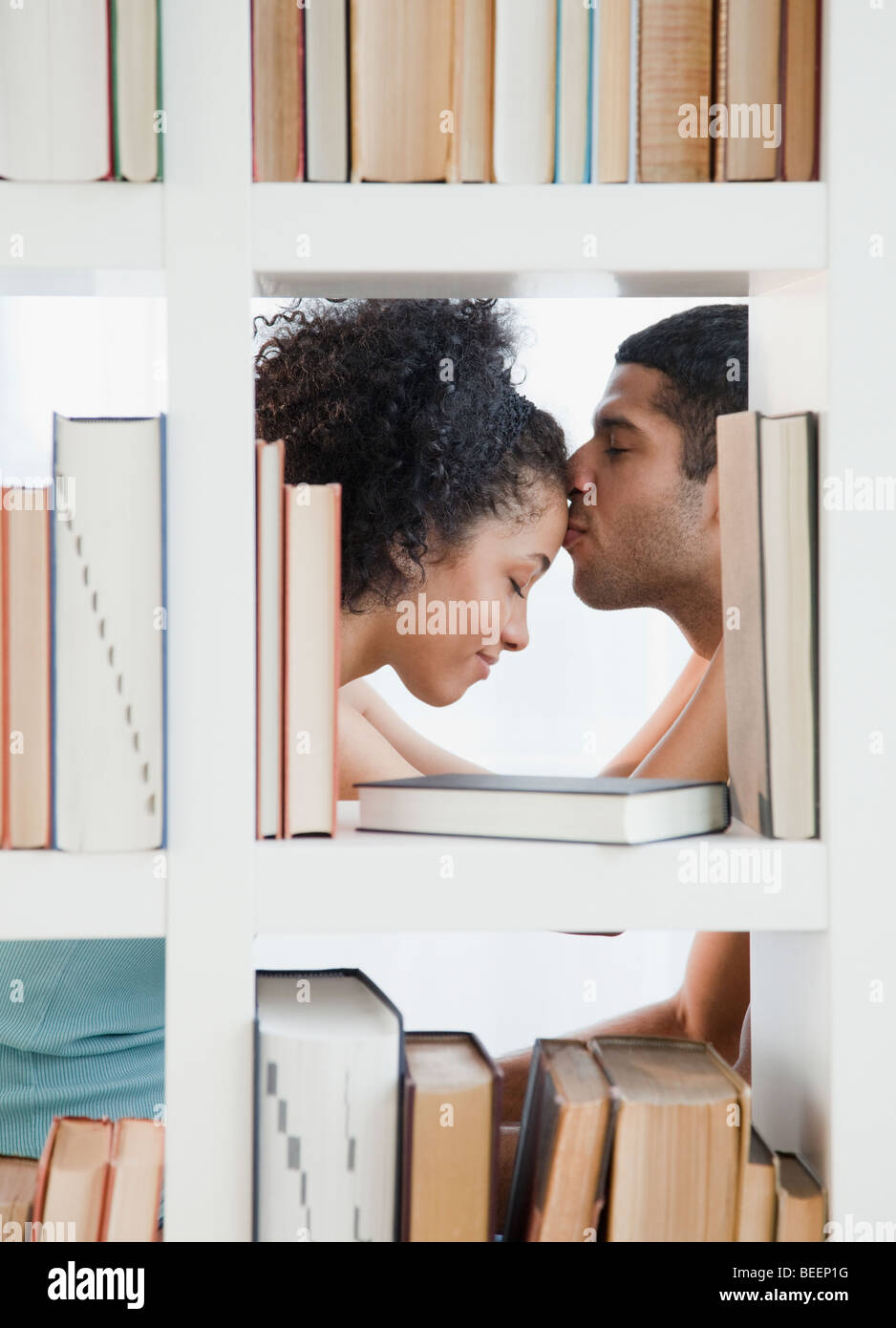 Couple kissing by bookcase Stock Photo