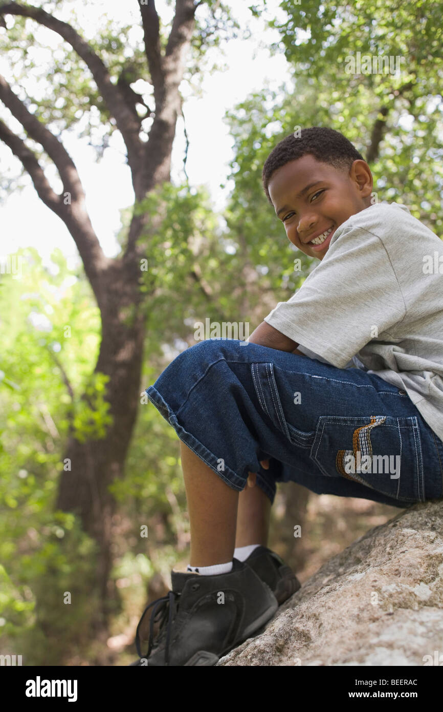 African boy sitting on rock in park Stock Photo
