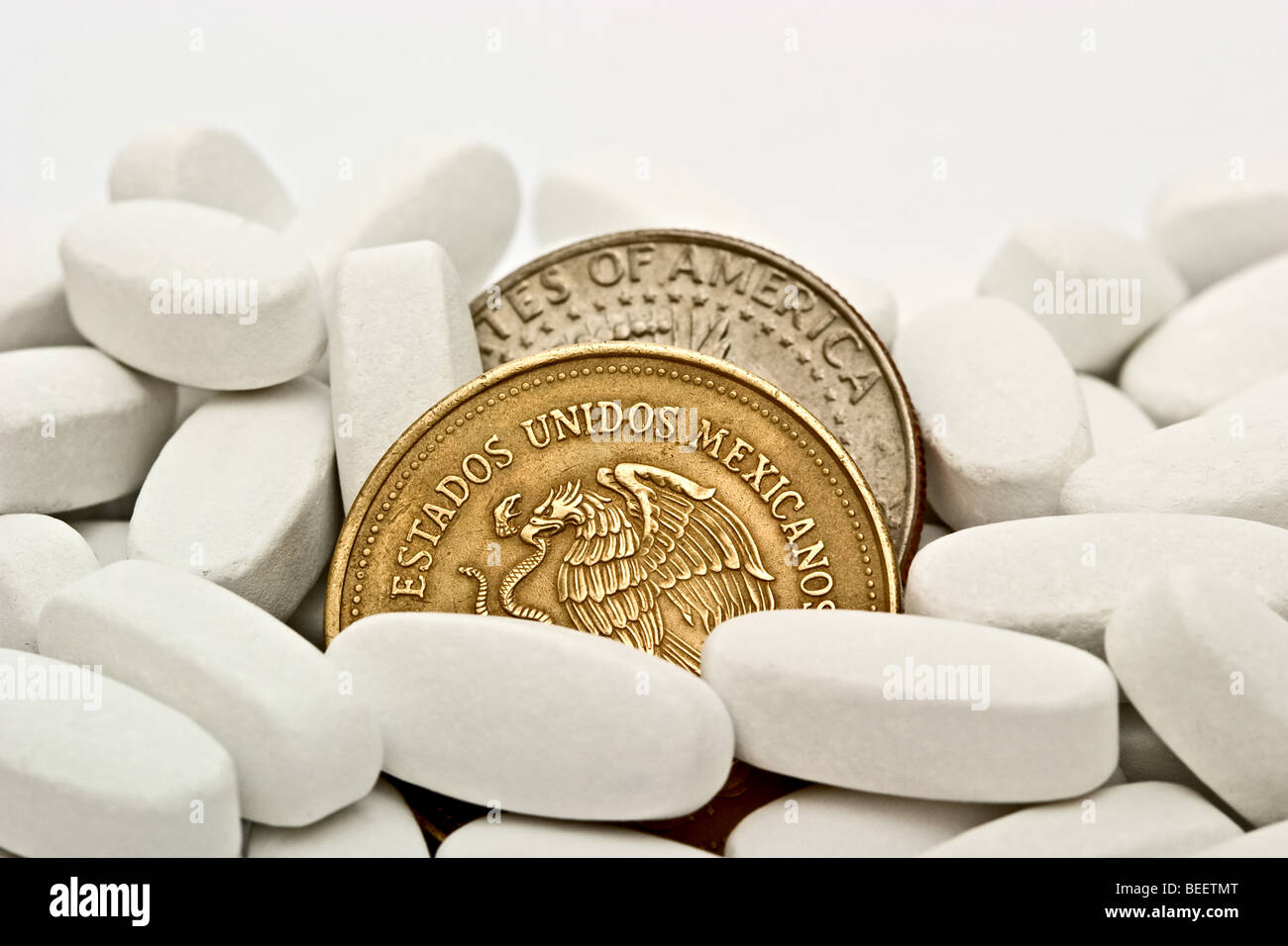 White pills and a Mexican thousand peso coin and an American silver half dollar Stock Photo