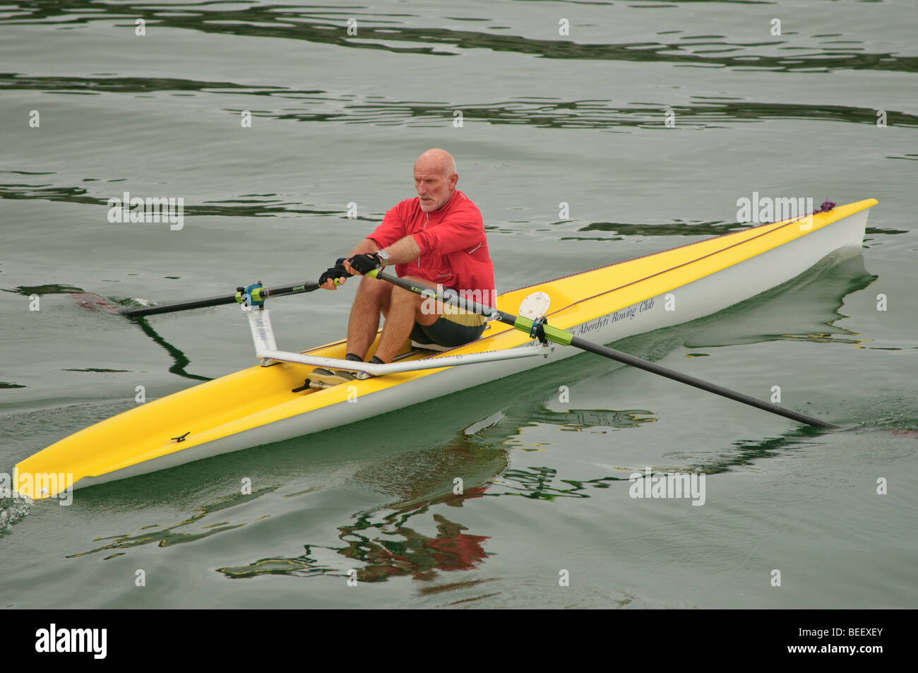 A healthy fit middle aged man sculling alone in a single seater solo scull rowing boat canoe kayak, UK Stock Photo