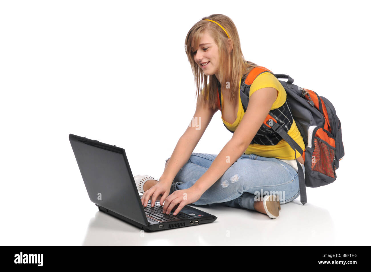 Tenn student with laptop typing and sitting on the floor Stock Photo