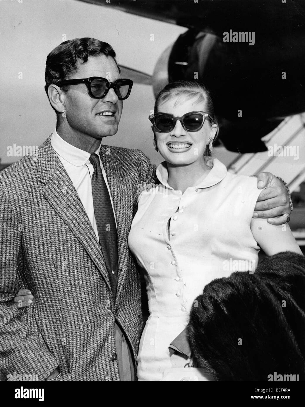 Swedish actress Anita Ekberg with her husband, British actor Anthony Steele, arriving at London Airport in 1956. Stock Photo