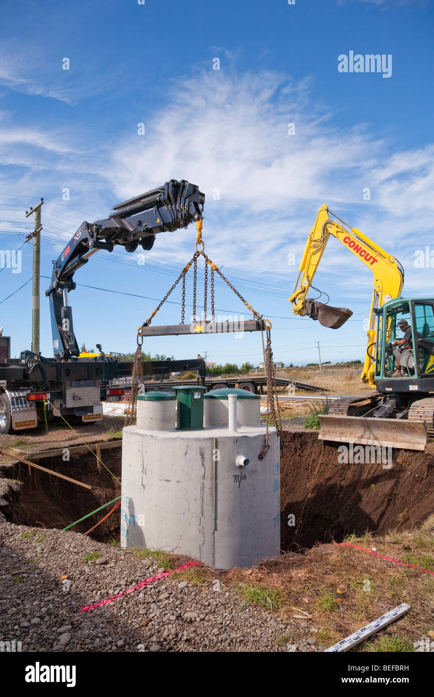 Domestic sewage treatment tank being lowered into position on construction site. Stock Photo