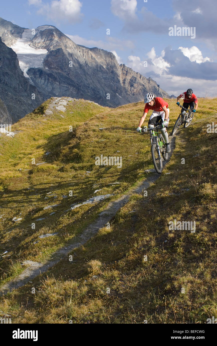 Two mountain bikers ride a trail near Les Arcs in the French Alps. Stock Photo