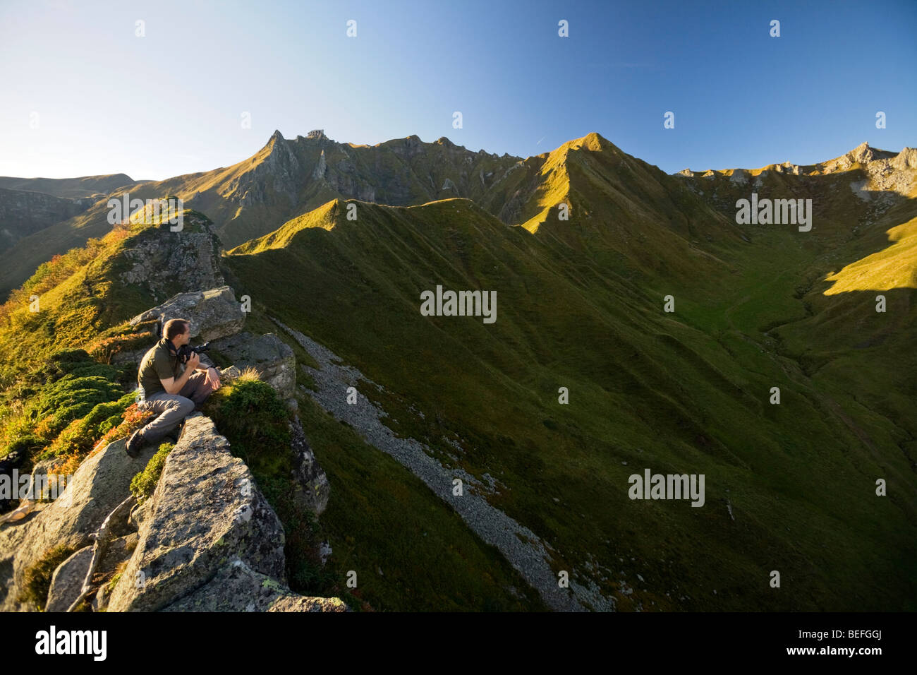Early in the morning, a photographer gazing at the "Val de Courre" (Auvergne). Photographe admirant le Val de Courre au matin. Stock Photo
