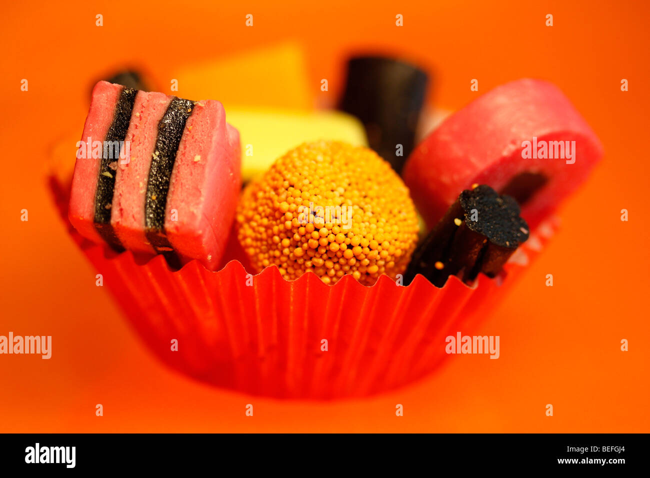Liquorice Allsorts in red cupcake paper case against orange background