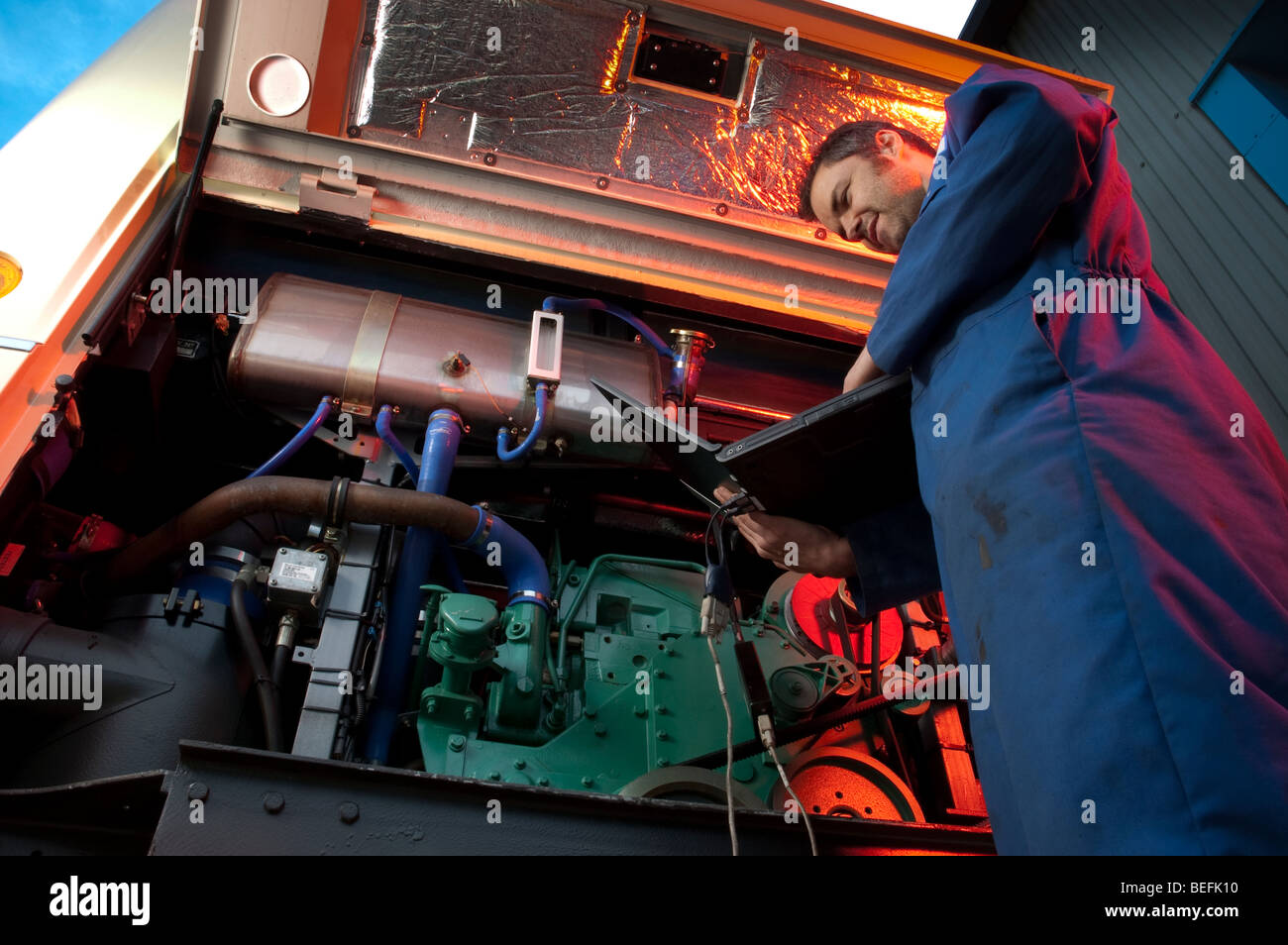 Motor mechanic using computer to set up and diagnose a coach engine Stock Photo