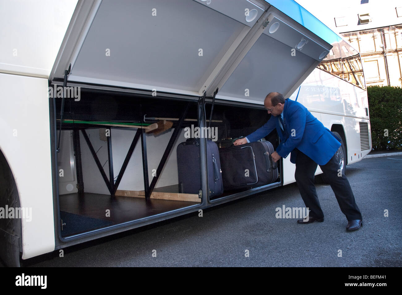 driver Loading luggage into luggage hold of a coach Stock Photo Alamy