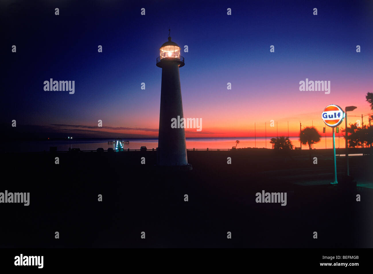 The Old Biloxi Lighthouse on Gulf of Mexico in Mississippi with passing traffic at dusk Stock Photo